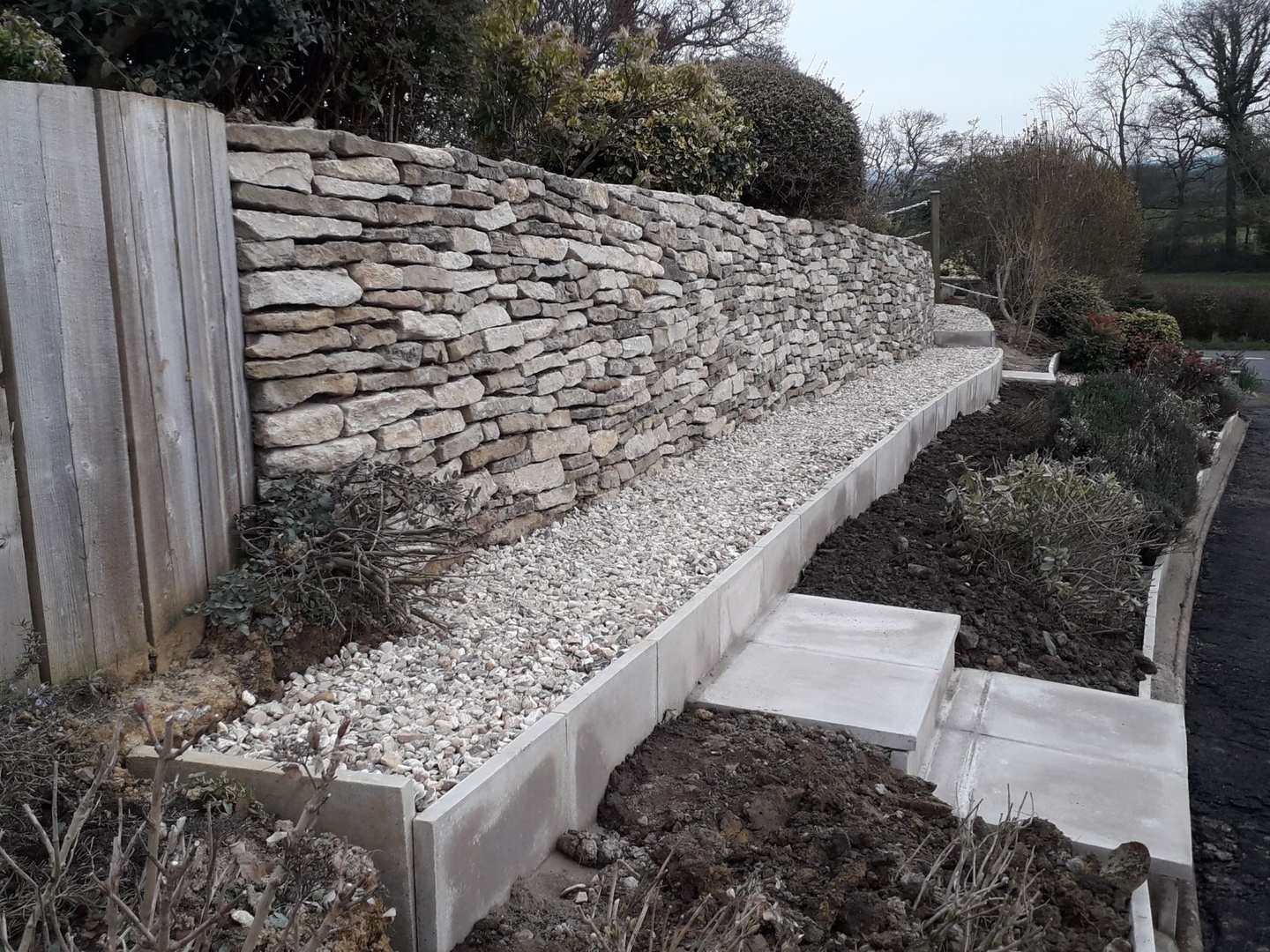 Wall rebuilt, bank made accessible, kerbing added